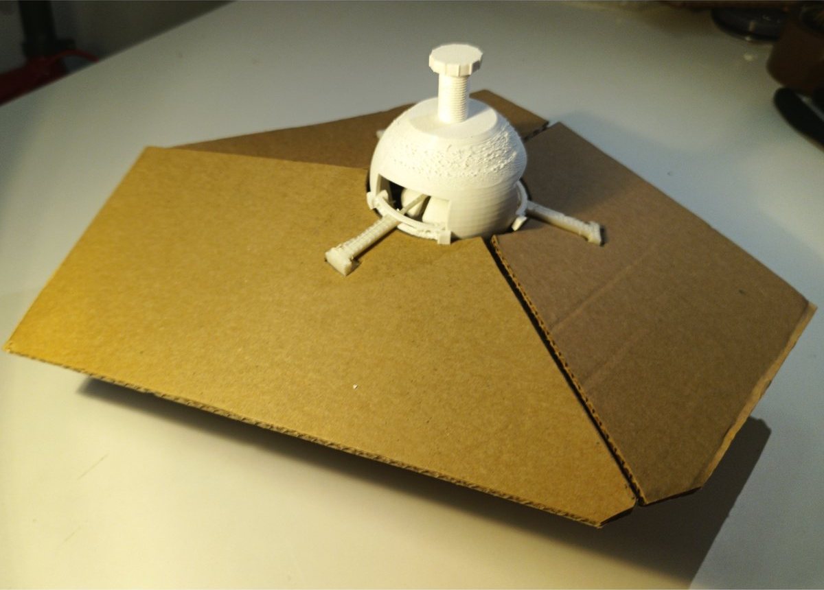 A 3D-printed vertex joint locking three cardboard panels together at an angle